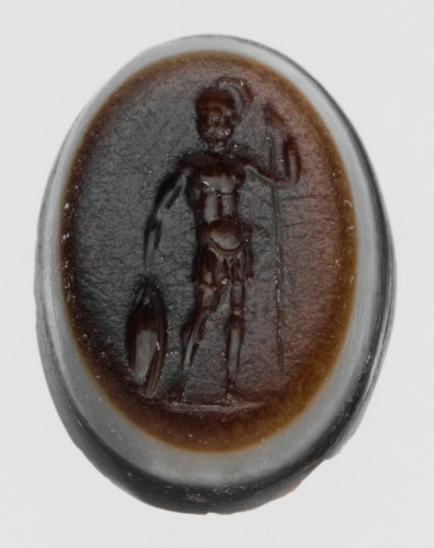 Sardonyx gem engraved with Ares or Mars standing upright in full armour, a crested helmet on his head. He holds up a spear and a round aspis shield is on the ground by his side, steadied by his hand.