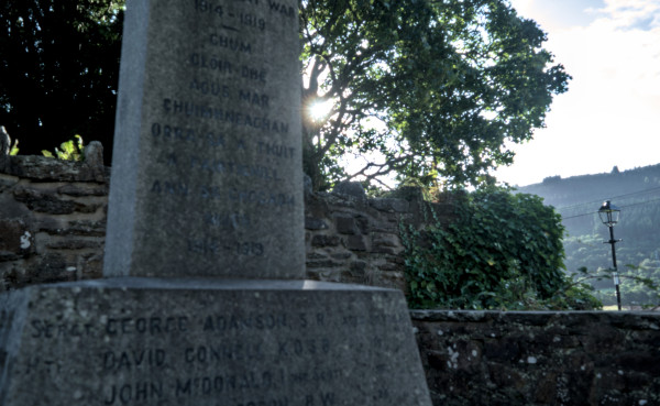 Fortingall war memorial with Gaelic text and sunrise behind trees