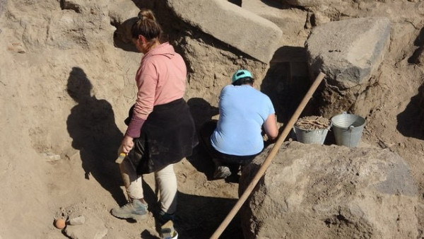 two archaeologists standing in a dig.