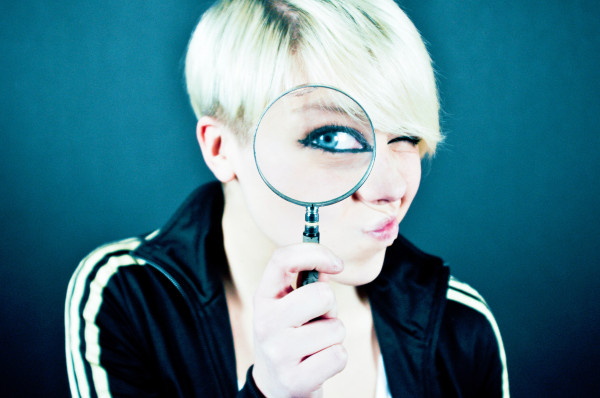 Photo of a bottle blond woman with a pixie haircut donning a navy track jacket peering through a magnifying glass with her mouth puckered and twisted to the left side of her face.

Photo by Emiliano Vittoriosi on Unsplash.