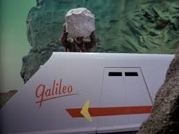 Furry alien chucking a huge bolder at the Galileo shuttle craft