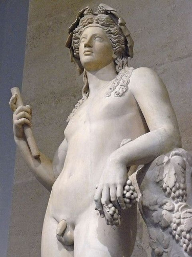 Marble sculpture of the god Dionysos. He is crowned with a thick ivy or grapevine wreath with small clusters of grapes or berries at the parting of his hair. A fillet is bound into his rich hair right above the forehead and lush locks fall down over his shoulder. The god is in the nude, leaning on a column and holding a cluster of grapes and the remains of a staff. But the arms and legs were heavily restored in the 18th century, so we don't know for sure what he originally looked like.