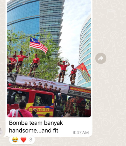 A WhatsApp screenshot where someone approvingly shares a photo of muscular firefighters showing off their assets on top of a fire truck during the Merdeka Day Parade, to the delight of many others in the WhatsApp group.
