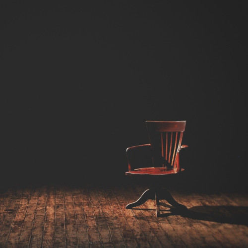 A wooden rolling chair in a dark room with a wooden floor.