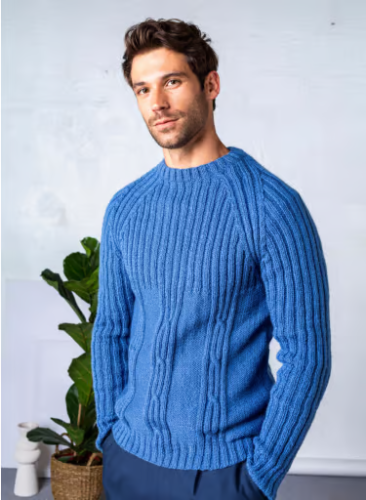 A photo of a man wearing a blue ribbed and cable knit sweater