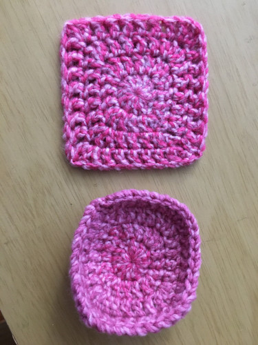 Two squares crocheted in the same pink and gray yarn. The square on top is a proper square shape and it laying flat. The square on the bottom is curled up on the edges and looks more like a bowl.