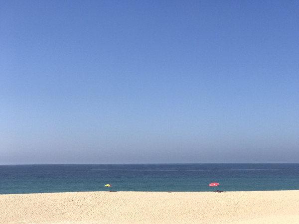 Plage presque déserte, 2 parasols et un grand ciel bleu . Côte Vicentine. Portugal