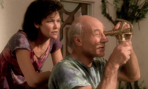 Picture of Captain Picard, sitting down looking through a telescope with his wife, Eline, behind him.