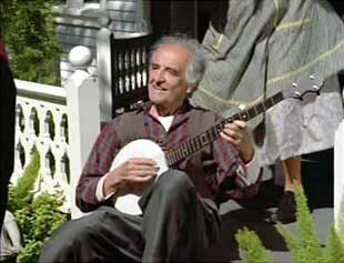 The Caretaker portrayed as a manifestation of an older country man playing a banjo on a farmhouse porch 