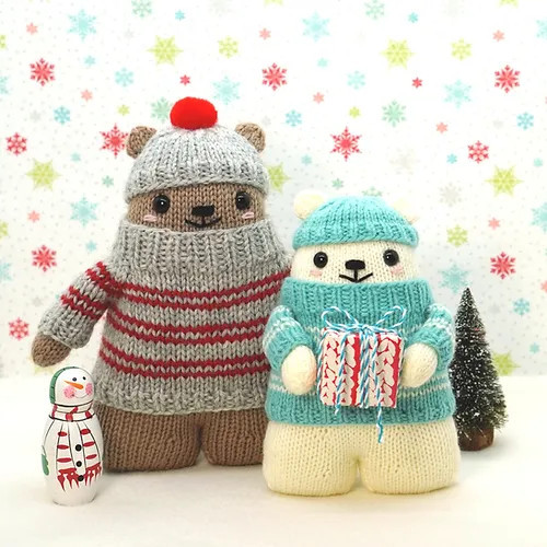 Two bears, one white with a teal sweater with white stripes and teal hat, one brown with a gray sweater with red stripes and gray hat.