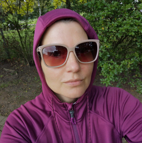 Selfie of me, a female person wearing sunglasses and a purple hoodie that completely covers her head and neck.