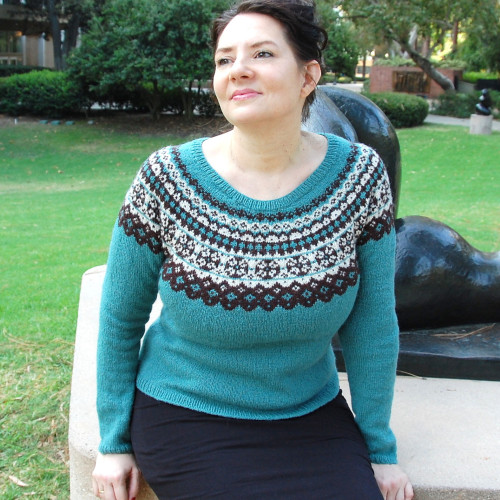 Medium aqua close-fitting sweater with a circular yoke worked in intricate stranded knitting patterns of black and white. Rounded neckline, hip-length, long sleeves.