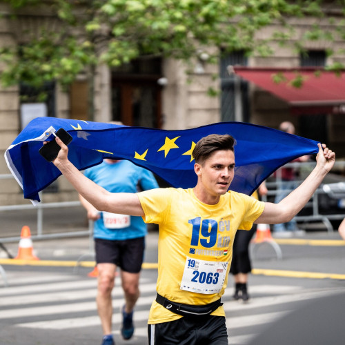 Photograph from Europe Day run in Budapest with one person in a yellow shirt and holding the EU flag.
