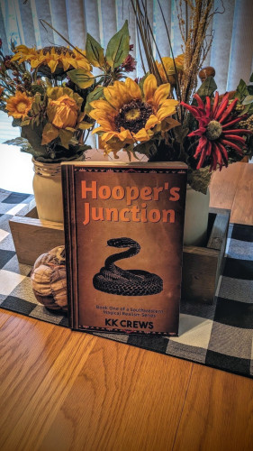 A paperback copy of the book Hooper's Junction sits propped up against some flowers