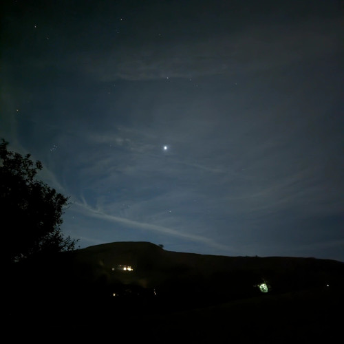 Jupiter shining big and bright against a fairly clear dark night sky above the silhouette of the valley tops.