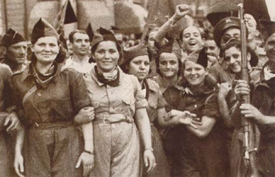 Spanish anarchist milicianas in Barcelona, in July 1936. Sepia toned B&W photo of a large crowd of women standing in the street wearing forage caps,overalls and scarves tied around their necks. Smiling at camera, woman photo right holding gun pointing upwards. 