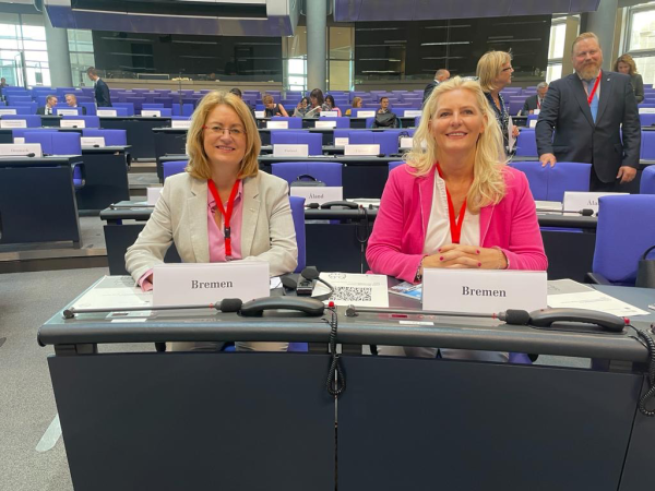 Antje Grotheer (links) und Christine Schnittker (rechts) sitzen an einem Tisch im Plenarsaal des Deutschen Bundestages.