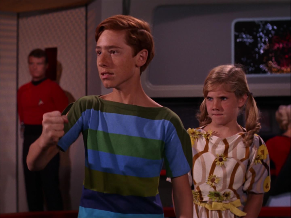 Still image from Star Trek episode "And the children shall lead them". Teenage boy in a striped shirt making a fist, while a younger girl with pigtails watches.