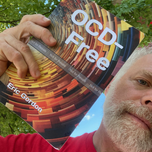 I am outside, holding an author's proof copy of my book, OCD-Free