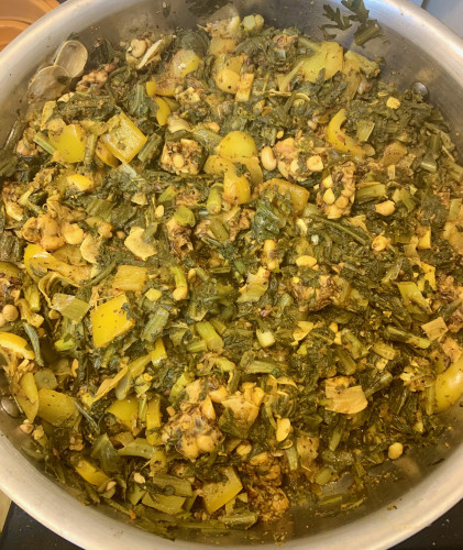 A pan of greens with yellow bell pepper, diced lemon, and tempeh. 