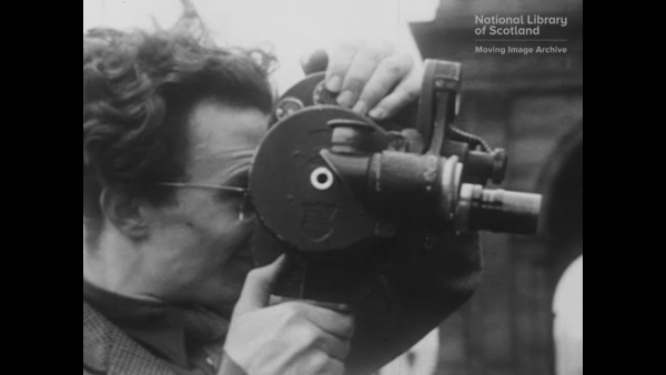 Man looks into eyepiece of old fashioned movie camera