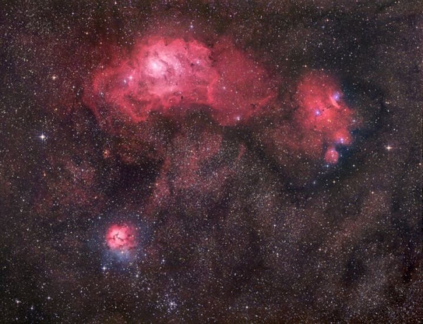 These three bright nebulae are often featured in telescopic tours of the constellation Sagittarius and the view toward the center of our Milky Way galaxy. In fact, 18th century cosmic tourist Charles Messier cataloged two of them; M8, the nebula above and left of center, and colorful M20 at the lower left. The third, NGC 6559, is at the right of M8, separated from the the larger nebula by a dark dust lane. All three are stellar nurseries about five thousand light-years or so distant. The expansive M8, over a hundred light-years across, is also known as the Lagoon Nebula while M20's popular moniker is the Trifid. In this gorgeous digital composition, the dominant red color of the emission nebulae is due to glowing hydrogen gas energized by the radiation of hot, young stars. The contrasting blue hues, most striking in the Trifid as well as NGC 6559, are due to dust reflected starlight.

Robert Gendler