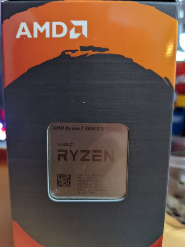 Photograph of retail packaging of an AMD CPU. The text printed on the CPU is visible and AMD Ryzen 7 5800X3D