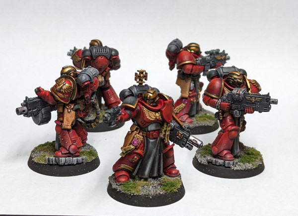 Warhammer 40k Space Marine Sternguard Veterans squad painted in a Blood Angels scheme with red and black armor and gold helms and shoulders.