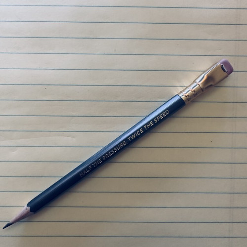 A Blackwing wooden pencil, inscribed &lsquo;half the pressure twice the speed&rsquo; rests on a yellow legal pad.