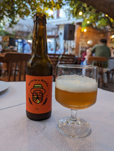 Bottle of beer with glass on table. Bottle says: "Beer of the old men" in Albanian.