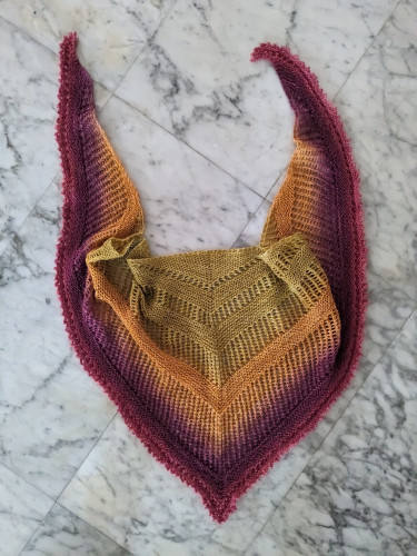 A handknit triangle shawl with alternating bands of eyelets and garter, with a pivot hem, in a green-yellow-purple-pink gradient.