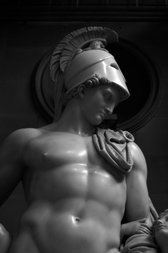 The God of War is in the nude, wearing only a crested helmet and a cloth draped over one shoulder. He is looking down to his left, where Cupid has taken his arm, looking up at his father.