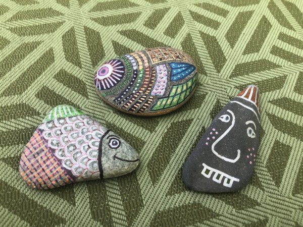 Three painted rocks: one looks like a fish, another looks like a goober with a dunce cap and one looks like I don’t know what possibly another fish
