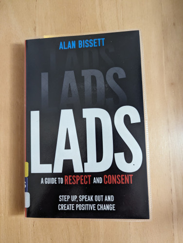 The front cover of "Lads" by Alan Bissett with the subtitles "A Guide to Respect and Consent" and "Step Up, Speak Out and Create Positive Change". It has a plain black background with mostly white lettering, but some blue and red letters. 