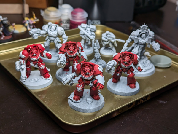 Warhammer 40k Space Marines in Termination Armour partially painted. Primed white with a base coat of red on four of them.
