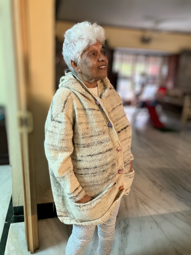 My mother modeling her new hoodie. She looks to the right and has her hoodie pulled back and buttoned up. I have blurred the background.