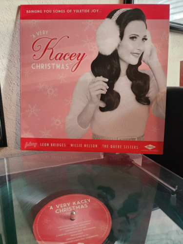 Kacey Musgraves - A Very Kacey Christmas album cover. Kacey with white fuzzy earmuffs on.