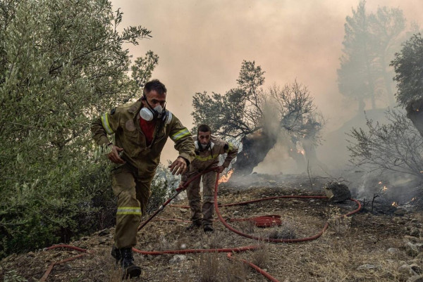 Photo of firemen battling flames burning vegetation during a wildfire near Prodromos, Greece. Photo by SPYROS BAKALIS/AFP via Getty Images 