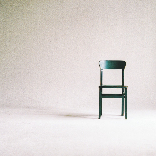 A dark green chair in an empty white room