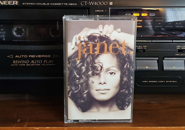 Cassette case sits in front of a cassette player. The cassette case shows Janet Jackson head pic, and says "janet." 