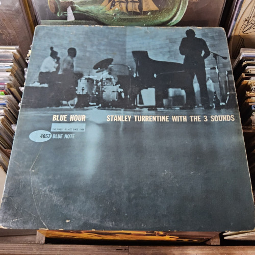 Album cover features a blue-tinted, blurry photograph of the musicians performing in the studio.  ST is seen playing the sax, with his back to the camera, and a bottle of wine on the floor near his feet.  It's an unusual photo, not only because it's blurry, but because the bottom half of the photo shows the glossy cement studio floor.
