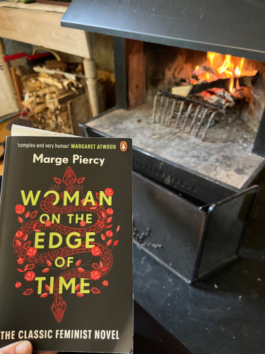 Black, red and yellow book cover Women on the Edge of Time by Marge Piercy. "The Classic Feminist Novel". With black fireplace and orange flames in the background.