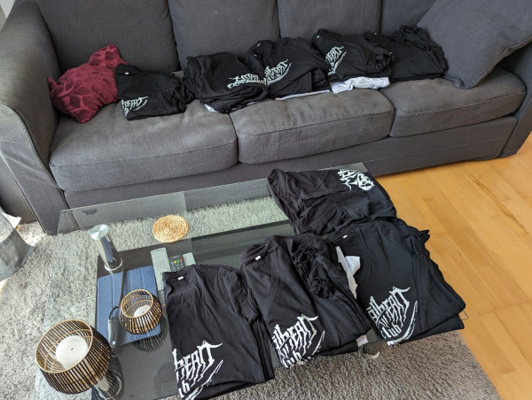 Multiple batches of metalhead.club t-shirts in my couch and living room table.