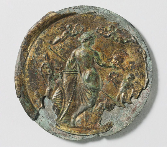 Venus Victrix, Venus the Victorious, on a mirror case. The goddess shows her bare backside while she holds up a crested helmet. Two winged erotes holding laurel wreaths fly above her head.