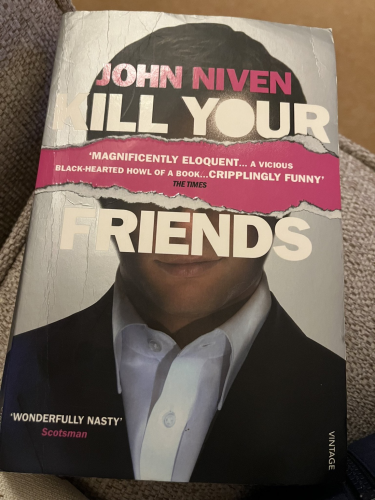 Front cover of Kill Your Friends with the top and bottom sections of a man’s head in a suit with a rip effect across the page where his eyes would be.