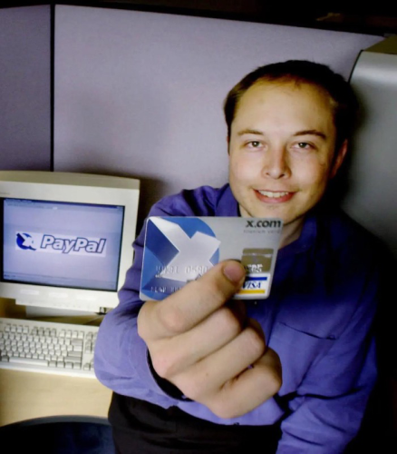 Elon Musk showing off an X.com Visa card and the computer behind him shows the logo for X-PayPal.