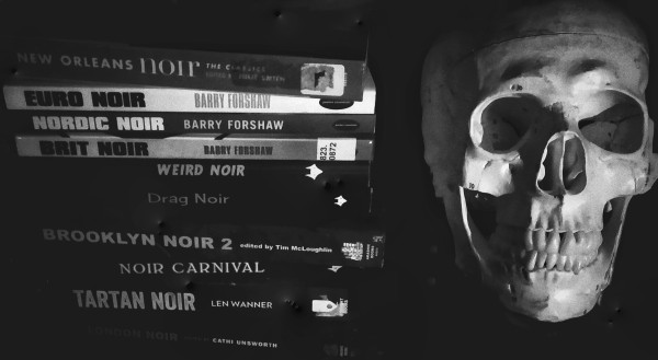 Pile of Noir-themed books on shelf next to anatomical human skull model. 
