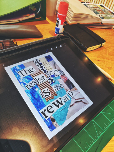 An iPad open to a phot of a collage with the words "the Resistance is the reward" in cut out letters. The iPad is sitting in a green cutting mat. On a wooden table. Beside notebooks and art supplies.