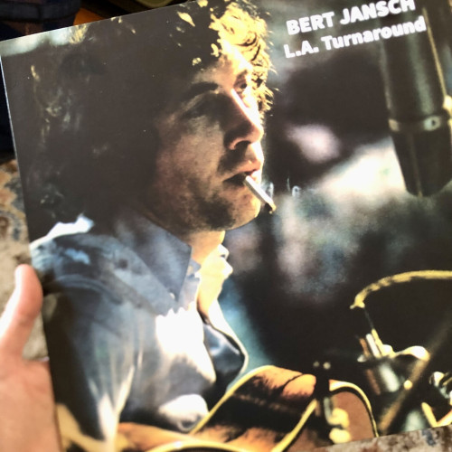 Cover of Bert Jansch’s album, L.A. Turnaround. Image is Bert sitting with his guitar at a microphone, cigarette hanging from his lips.