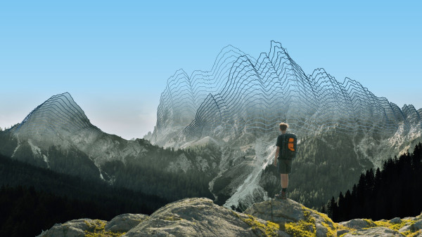 Alpine scenery. In the distance, the mountains are graphically represented as wireframes that gradually fade into the photograph below. In the foreground, looking towards the mountain range, is a lone hiker standing on a cliff edge